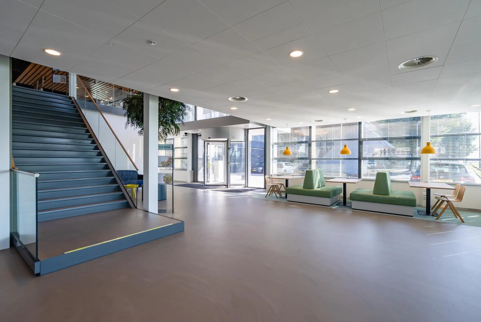 Moderne entreehal van Rivium Promenade met trap, zitgedeelte en grote raampartijen.